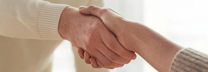 2 personer der giver hånd