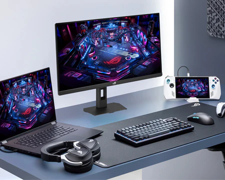 ROG Strix XG27ACMEG på bord med bærbar PC og spillekonsol