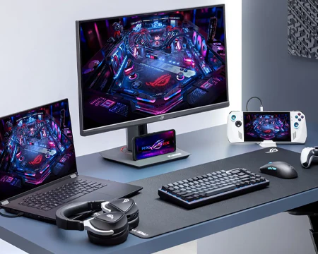 ROG Strix XG27UCS på bord med bærbar PC og spillekonsol